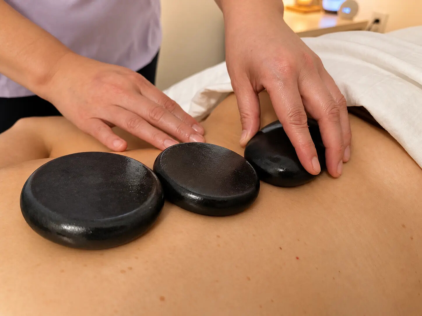 A practitioner placing warmed stones during a treatment